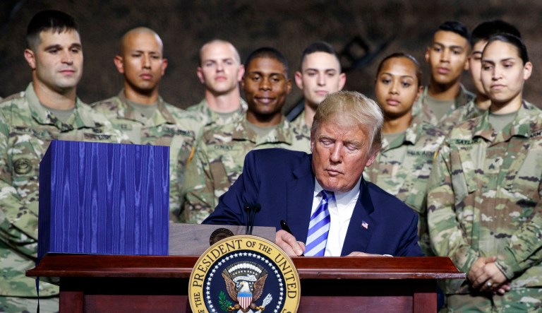 President Donald Trump signs the $716 billion defense policy bill named for Sen. John McCain at Fort Drum, N.Y., Monday, Aug. 13, 2018.