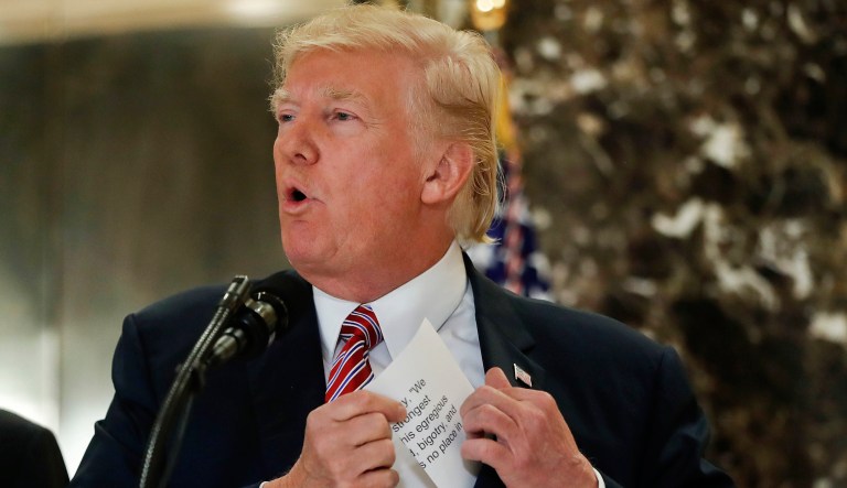 President Donald Trump reaches into his suit jacket to read a quote he made on Saturday regarding the events in Charlottesville, Va., as he speaks to the media in the lobby of Trump Tower in New York, Tuesday, Aug. 15, 2017.