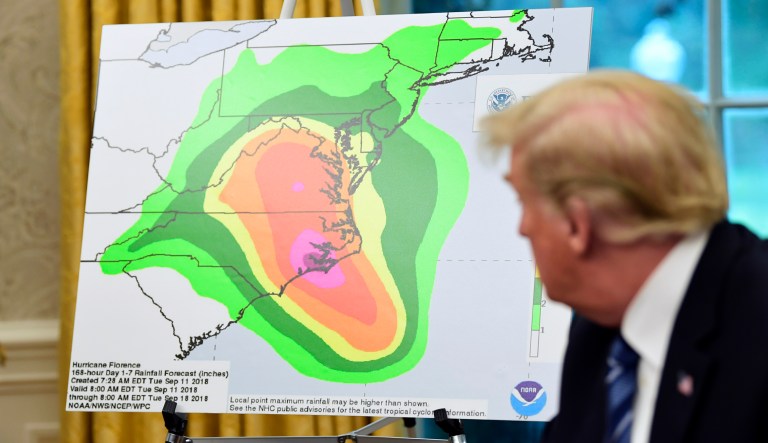 President Donald Trump looks at a chart showing potential rainfall totals from Hurricane Florence during a briefing in the Oval Office of the White House in Washington, Tuesday, Sept. 11, 2018.