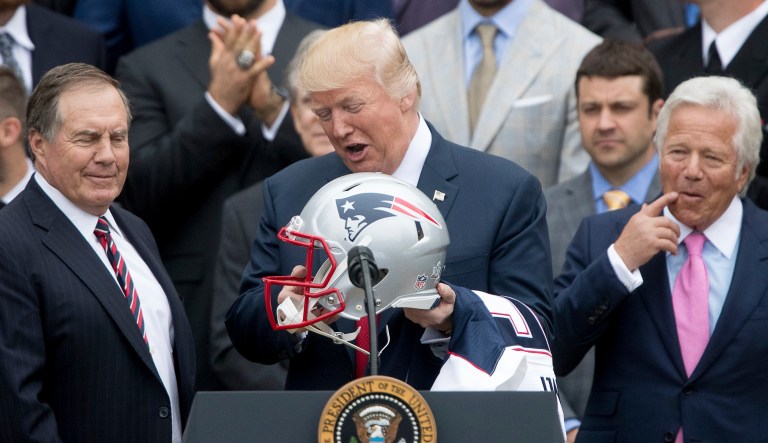 DAY 90 - In this April 19, 2017, file photo, President Donald Trump. flanked by New England Patriots head coach Bill Belichick, left, and owner Robert Kraft, holds a New England Patriots football helmet and jersey during a ceremony on the South Lawn of the White House in Washington, where he honored the Super Bowl Champion New England Patriots for their Super Bowl LI victory.