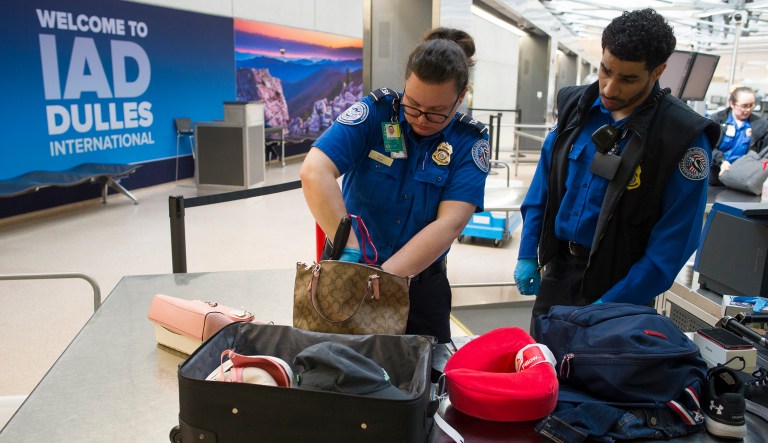 Transportation Security Administration (TSA) Officers search handbags which were packed in a suitcase at a checkpoint at Dulles International Airport in Dulles, Va., Tuesday, March 26, 2019.