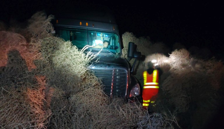In this image taken Tuesday evening, Dec. 31, 2019, and provided by the Washington State Patrol, a vehicle is trapped by a pile of tumbleweeds along State Route 240 near Richland, Wash.