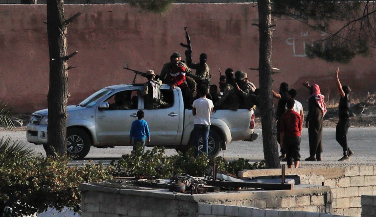 In this photo taken from the Turkish side of the border between Turkey and Syria, in Akcakale, Sanliurfa province, southeastern Turkey, Turkish-backed Syrian opposition fighters celebrate in Tal Abyad, Syria, Sunday, Oct. 13, 2019. 