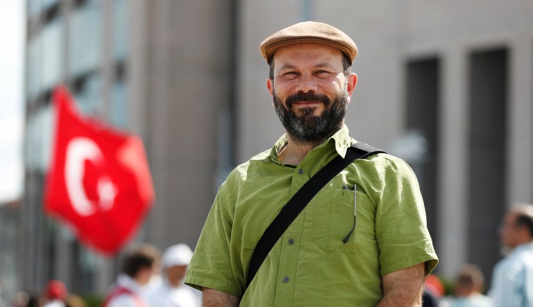 Baki Tezcan, a professor at UC Davis in California, poses for photos outside a court in Istanbul, where he was to stand trial, Thursday, July 18, 2019.