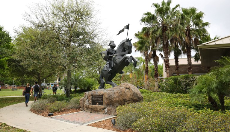 Orlando, Florida, USA - March 28, 2016:  Students walk past the University of Central Florida's Victory Knight statue, dedicated to the UCF Alumni and a popular graduation day photo spot.
