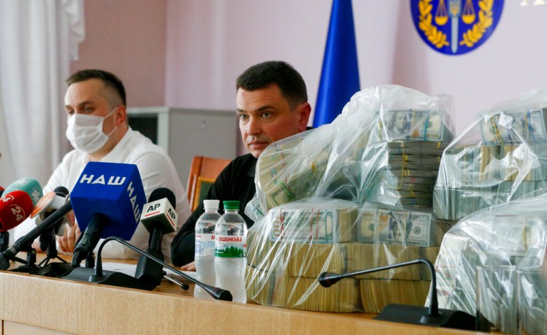 Nazar Kholodnytsky, left, and Artem Sytnik with a pile of $6 million in plastic bags.