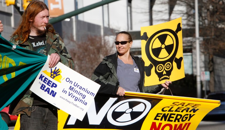 Protesters hold signs as they demonstrate against the push to remove the ban on uranium mining at the Capitol in Richmond, Va., Monday, Dec. 19, 2011.  The House uranium mining sub-committee was presented the National Research Council's study on Uranium Mining.