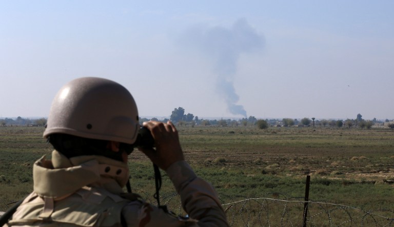 In this Tuesday, Nov. 13, 2018 photo, an Iraqi soldier watches smoke rising after an airstrike by US-led International coalition warplanes against ISIS, on the border between Syria and Iraq in Qaim, Anbar province, Iraq.