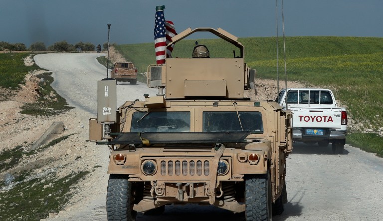 In this picture taken on Thursday, March 29, 2018, U.S. troop's humvee passes vehicles of fighters from the U.S-backed Syrian Manbij Military Council on a road leading to the tense front line with Turkish-backed fighters, at Halawanji village, north of Manbij town, Syria. The front line has grown more tense in recent days as Turkey threatens to advance on the town to clear it of the U.S-backed fighters. U.S troops have increased their patrols in the area, local commanders say, to prevent an outbreak of fighting and to prevent Turkey from advancing on Manbij.