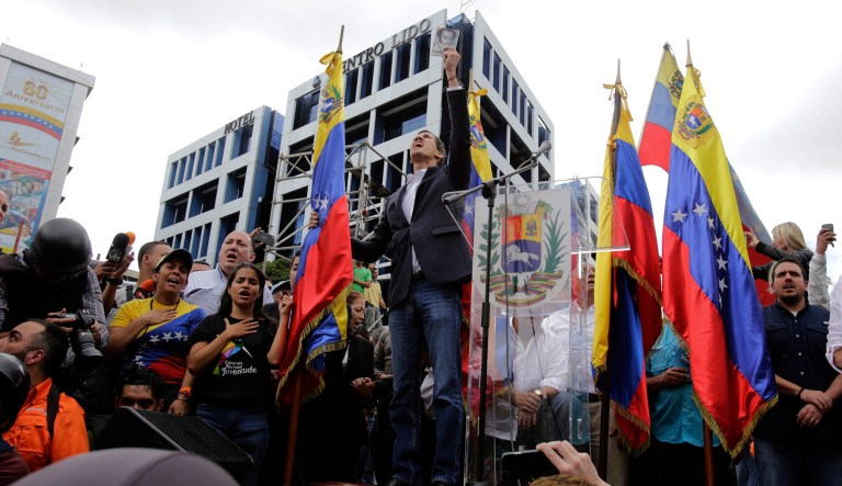 Juan Guaido, head of Venezuela's opposition-run congress, holds up a copy of the Venezuelan Constitution, after he declares himself interim president of the South American country until new elections can be called, at a rally demanding the resignation of President Nicolas Maduro, in Caracas, Venezuela, Wednesday, Jan. 23, 2019.