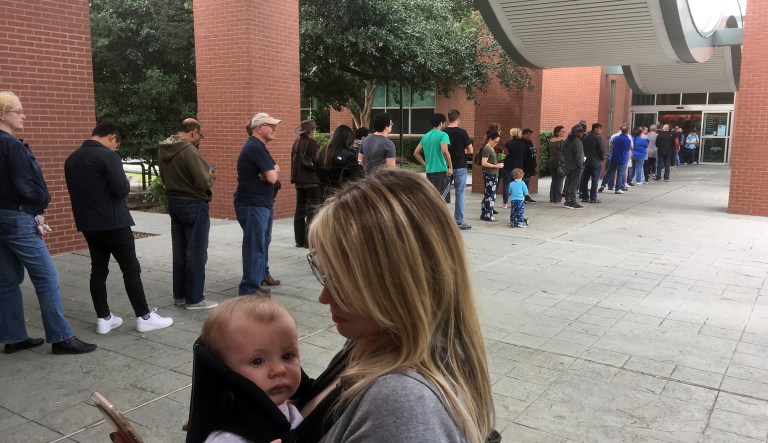 Megan Heckel of Plano holds her daughter Lily as they wait in line for early voting outside Maribelle M. Davis Library in Plano, Texas, Monday, Oct. 22, 2018.