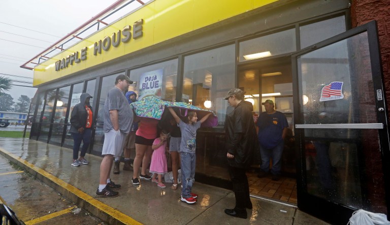 Luke Churchill, left, stands with his wife, Mary and their children, Katie,13, Liam, 9, and Raighan, 3, as they wait in the rain outside an open Waffle House restaurant in Wilmington, N.C., after Hurricane Florence traveled through the area Sunday, Sept. 16, 2018. 