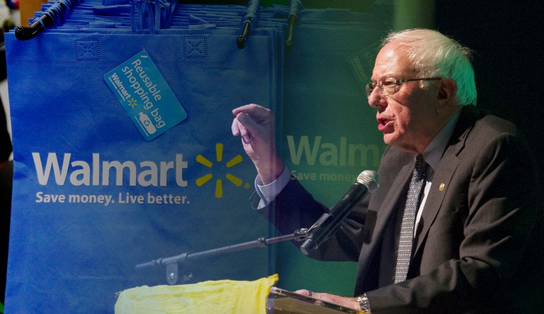 Bernie Sanders speaks at an event; Walmart bags with their respective logos are pictured behind him on the left.