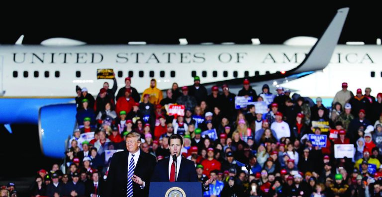 President Donald Trump listens as Republican Senate candidate Josh Hawley speaks during a campaign rally at Columbia Regional Airport, Thursday, Nov. 1, 2018, in Columbia, Mo. (AP Photo/Charlie Riedel)