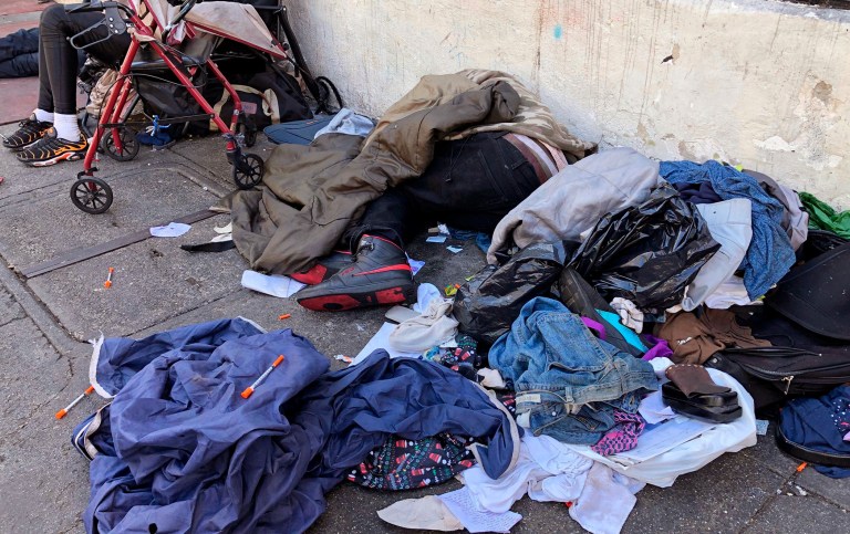 In this July 25, 2019, file photo, sleeping people, discarded clothes and used needles are seen on a street in the Tenderloin neighborhood in San Francisco.