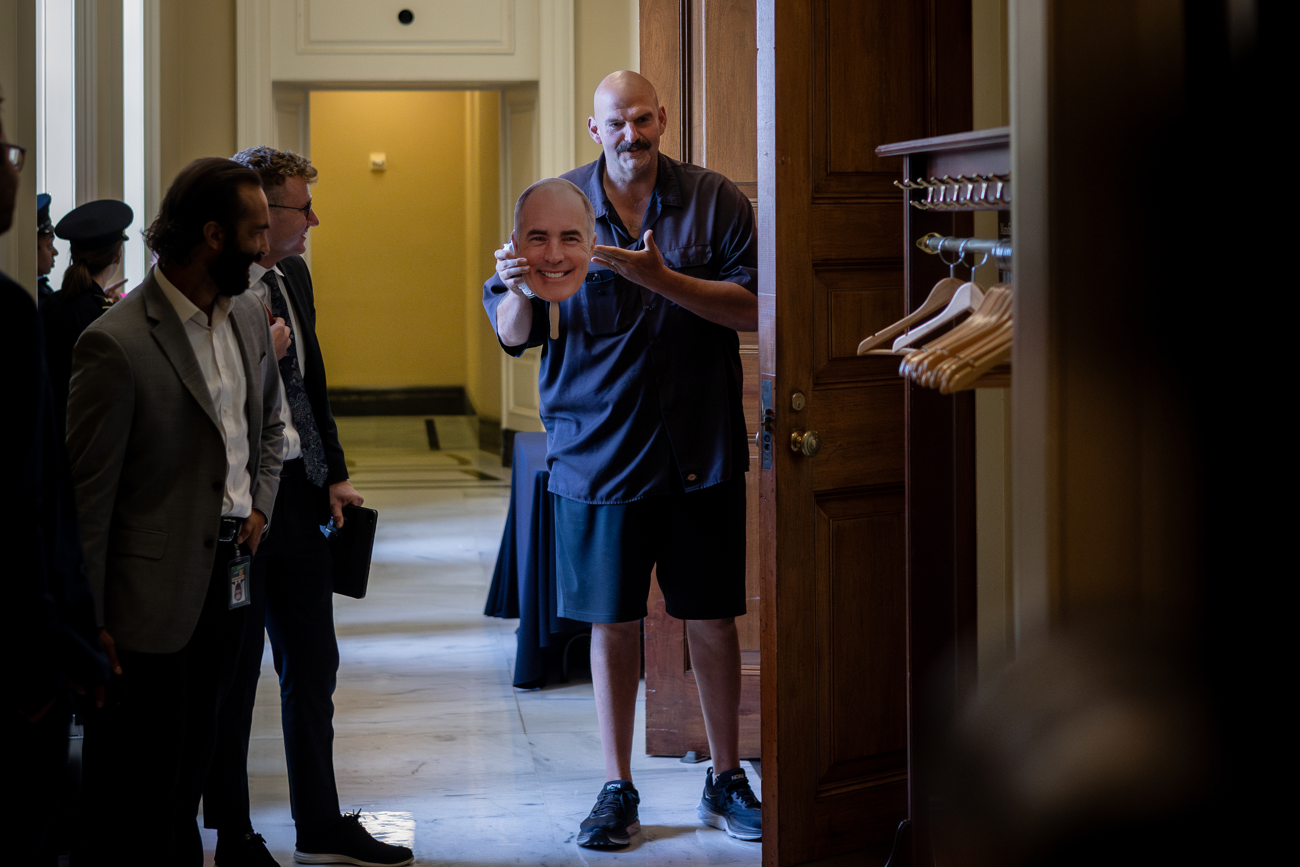 Sen. John Fetterman (D-PA) holds up a face mask of Sen. Bob Casey (D-PA)  on Sept. 20, 2023, before arriving at a Democratic luncheon on Capitol Hill. 