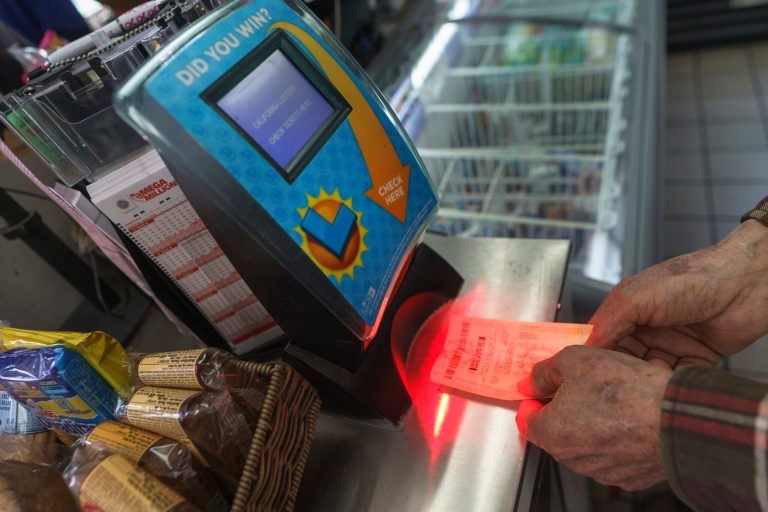 Roberto Ramirez checks his SuperLotto Plus ticket at a terminal at the gas station that previously sold the $2.04 billion-winning Powerball ticket award at Joe's Service Center, a Mobil gas station in Altadena, Calif., in 2023.  (AP/Damian Dovarganes)