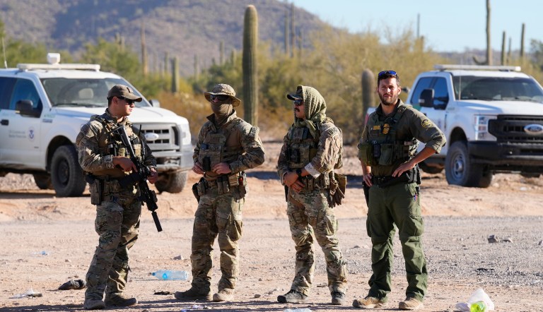 Members of the U.S. Border Patrol and U.S. Customs and Border Protection keep an eye on hundreds of migrants gathering along the border Tuesday, Dec. 5, 2023, in Lukeville, Arizona. The Border Patrol says it is overwhelmed by a shift in human smuggling routes, with hundreds of migrants from faraway countries like Senegal, Bangladesh, and China being dropped in the remote desert area in Arizona. 