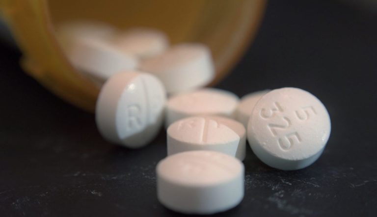 Opioid pills spill out of a prescription bottle.