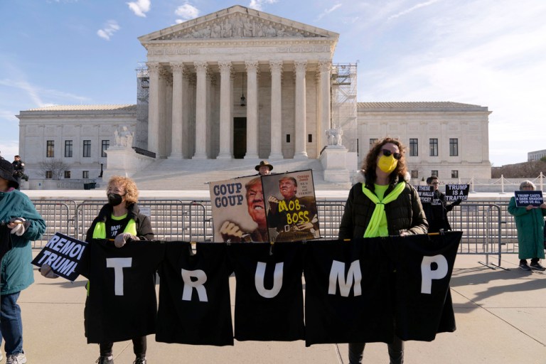 Demonstrators hold a banner outside of the U.S. Supreme Court, Thursday, Feb. 8, 2024, in Washington. The U.S. Supreme Court on Thursday will take up a historic case that could decide whether Donald Trump is ineligible for the 2024 ballot under Section 3 of the 14th Amendment. (AP Photo/Jose Luis Magana)