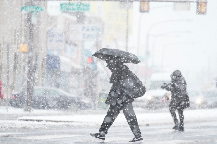People cross a street during a winter snow storm in Philadelphia