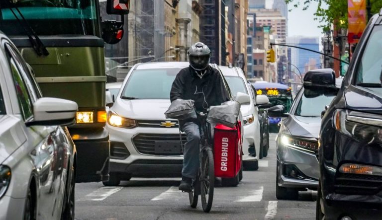 A food delivery worker rides through the a busy street.