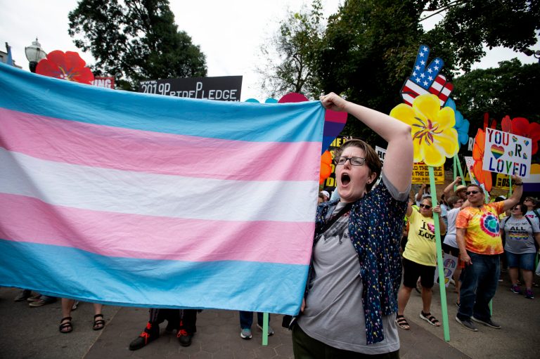 FILE - A supporter for the transgender community holds up a flag in front of counter-protesters at the city's Gay Pride Festival, Oct. 12, 2019, in Atlanta. Courts nationwide are delivering a mixed verdict on the future of state laws restricting gender-affirming medical care for transgender youth, as legal battles ramp up over the historic wave of bans enacted in 2023. (AP Photo/Robin Rayne, File)