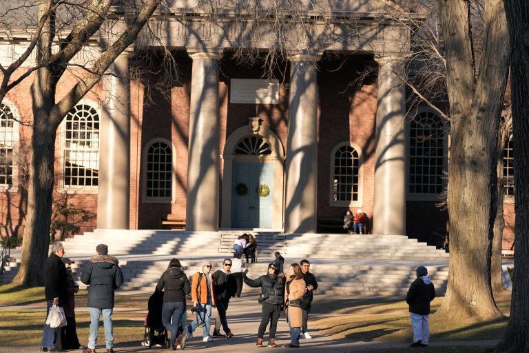 People pause for photographs, Tuesday, Jan. 2, 2024, on the campus of Harvard University, in Cambridge, Massachusetts. Former Harvard University President Claudine Gay resigned amid plagiarism accusations and criticism over testimony at a congressional hearing where she was unable to say unequivocally that calls on campus for the genocide of Jews would violate the school's conduct policy.