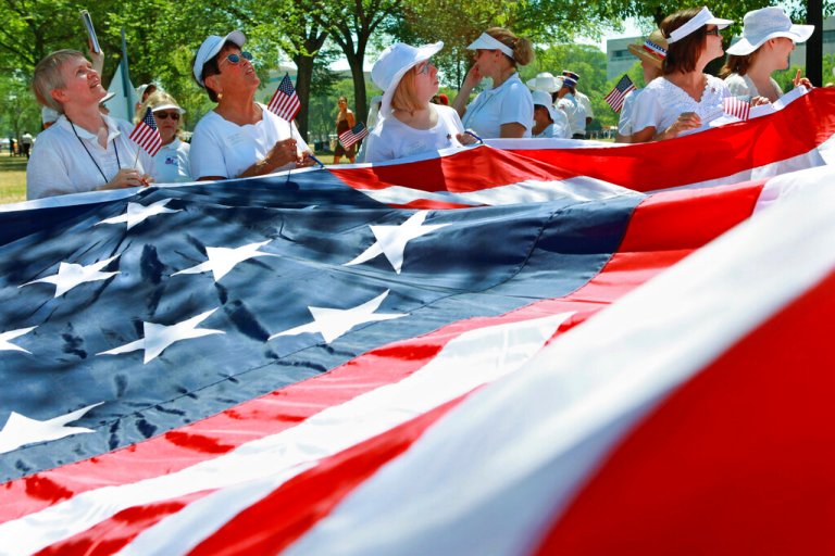 Members of the Daughters of the American Revolution hold a giant American flag during preparations on the National Mall in Washington before the before the Fourth of July, Independence Day, parade in Washington Sunday, July 4, 2010.