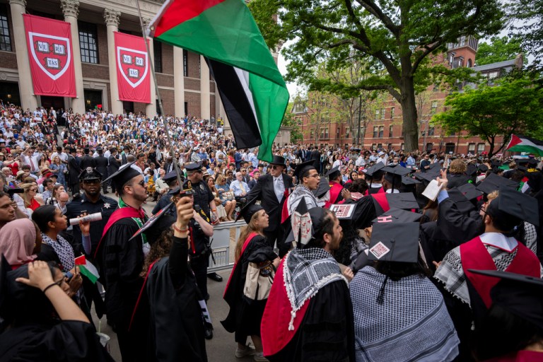 Graduating students hold Palestinian flags and chant as they walk out in protest over the 13 students who have been barred from graduating due to protest activities, during commencement in Harvard Yard, at Harvard University, in Cambridge, Mass., Thursday, May 23, 2024.