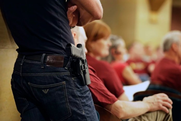 A Glock handgun is holstered on the side of Kristopher Kranz of Bloomington, Minnesota, as he listens during public testimony on Aug. 20, 2013, in St. Paul, Minnesota.