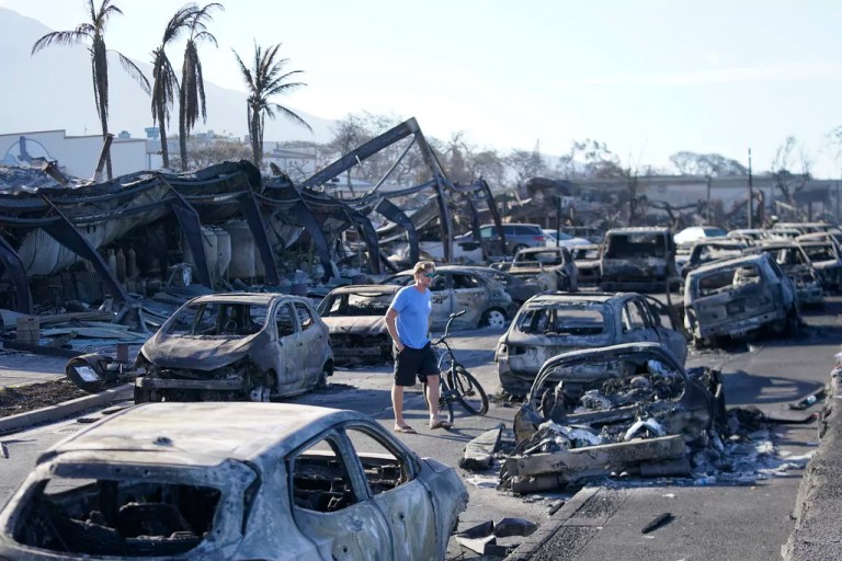 A man walks through wildfire wreckage Friday, Aug. 11, 2023, in Lahaina, Hawaii. Hawaii emergency management records show no indication that warning sirens sounded before people ran for their lives from wildfires on Maui that wiped out the historic town.