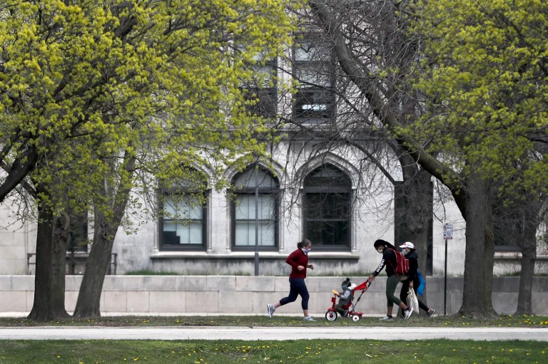 Pedestrians pass near the University of Chicago Monday, April 27, 2020, in Chicago. Anonymous comments with racist, sexist and abusive messages that were posted for years on a jobs-related website for economists originated from numerous leading U.S. universities, including Harvard, Stanford, and the University of Chicago, according to research released Thursday.