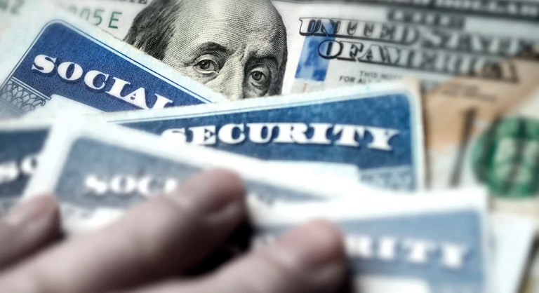 Several Social Security cards on a $100 bill. Social Security is a system of benefits for retired elderly people.