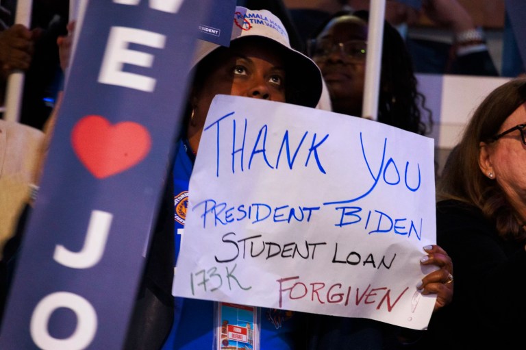 A woman holds a sign thanking President Joe Biden for forgiving her student loans during the first night of the Democratic National Convention.