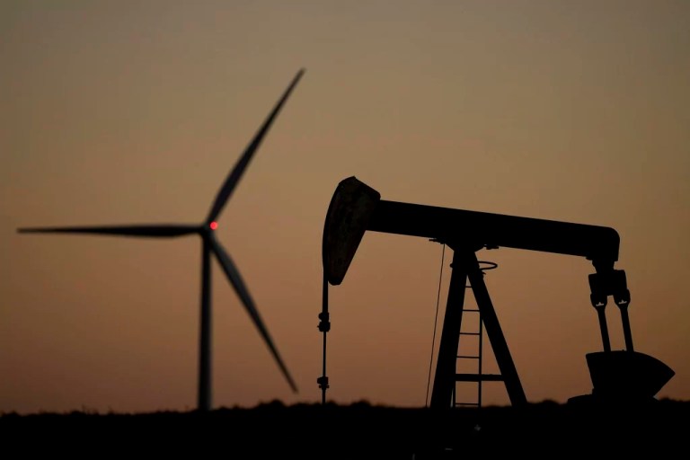 A pumpjack operates in the foreground while a wind turbine at the Buckeye Wind Energy wind farm rises in the distance, Monday, Sept. 30, 2024, near Hays, Kansas.