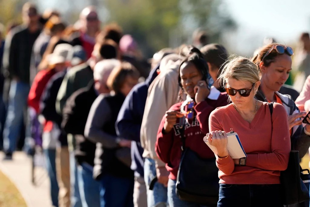 Vanessa Starke, from Lee's Summit, Mo., reads a book about halfway though her 90 minute wait in line to cast her ballot at an early voting location, Thursday, Oct. 31, 2024, in Blue Springs, Mo. (AP Photo/Charlie Riedel)