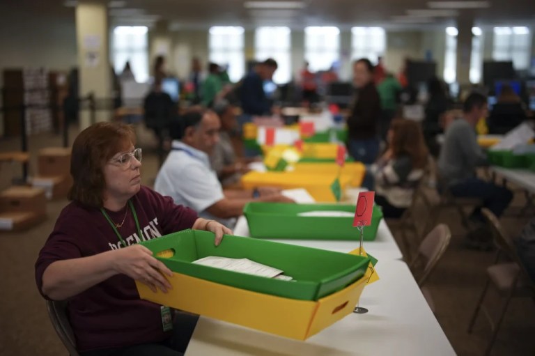 Election workers process mail-in ballots.