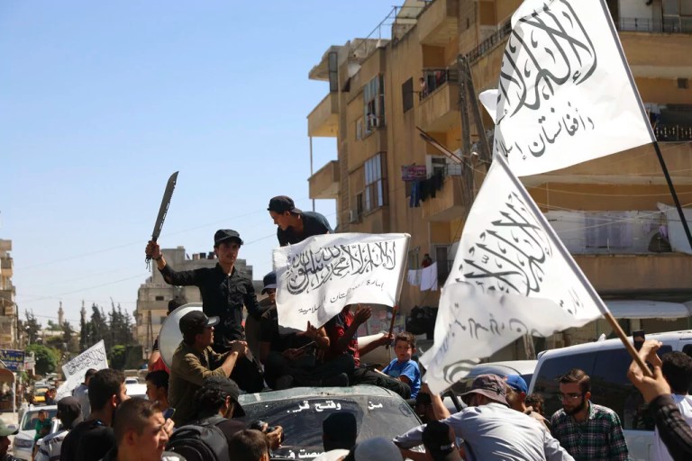 Members of the Hay'at Tahrir al Sham, a Sunni Islamist militant group, wave the Taliban flags as they celebrate the Taliban takeover of Afghanistan, in the city of Idlib, Friday, Aug. 20, 2021.