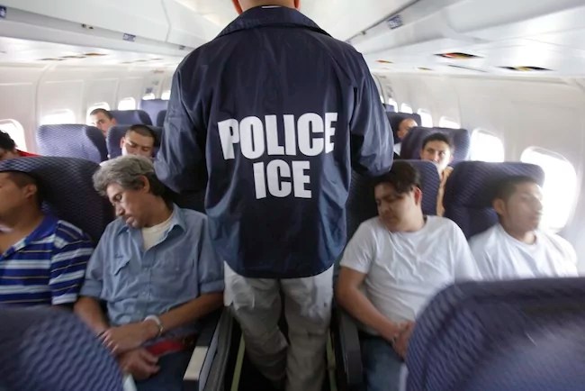 An Immigration and Customs Enforcement agent walks down the aisle among shackled Mexican immigrants aboard a U.S. ICE charter jet for deportation in the air between Chicago, Illinois, and Harlingen, Texas, Tuesday, May 25, 2010.