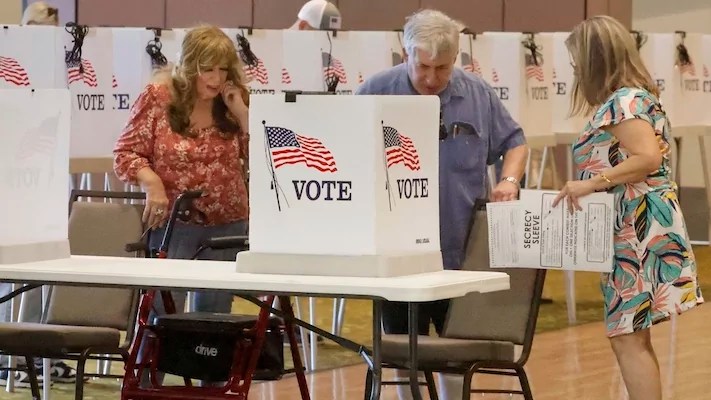 Mary Cohen, left, and ballot distributor Carol Scollan, right, help Marshall Solomon settle into a voting booth at precinct #83 at the Heritage Springs Clubhouse in Trinity, Florida, during the General Election, Tuesday, Nov. 5, 2024. (Douglas R. Clifford/Tampa Bay Times via AP)