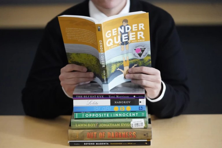 Amanda Darrow, director of youth, family, and education programs at the Utah Pride Center, poses with books that have been the subject of complaints from parents in recent weeks Thursday, Dec. 16, 2021, in Salt Lake City. Community leaders in Utah have said titles with characters and plot lines involving LGBT and minority students have been disproportionately targeted. Darrow said books such as 