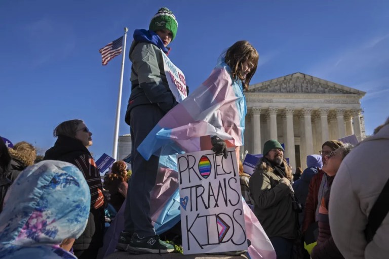 Nate, 14, left, and Bird, 9, right, hold signs and transgender pride flags as supporters rally outside the Supreme Court, Dec. 4, 2024, in Washington, while arguments are underway in a case regarding a Tennessee law banning gender-affirming medical care for transgender youth. (AP Photo/Jacquelyn Martin)