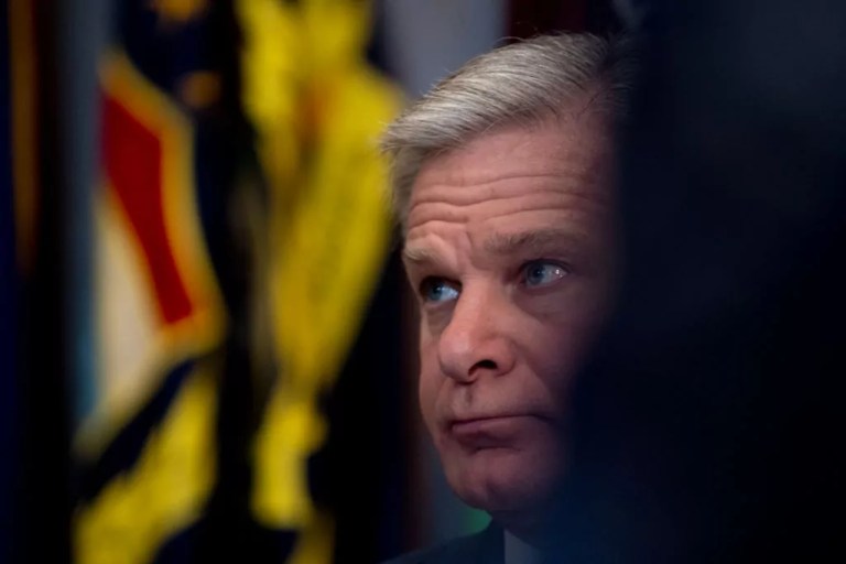 Christopher Wray seated in front of state flags