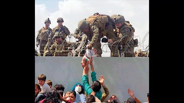 A baby is lifted over a wall at the Kabul airport in Afghanistan by U.S. soldiers as Afghans attempt to flee the Taliban takeover of the country, Aug. 19, 2021.