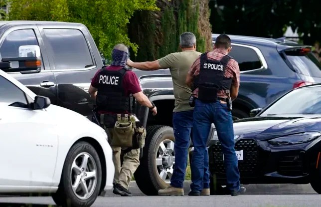 U.S. Immigration and Customs Enforcement agents arrest an immigrant outside his residence during an early morning raid in Duarte, Calif., Monday, June 6, 2022. (AP Photo/Damian Dovarganes)