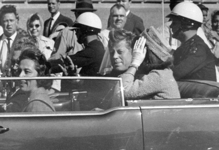 FILE - President John F. Kennedy waves from his car in a motorcade approximately one minute before he was shot, Nov. 22, 1963, in Dallas.