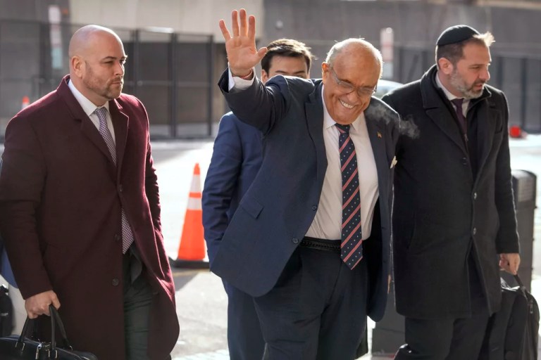 Rudy Giuliani waves as he arrives at federal court.