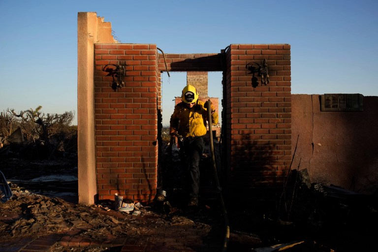 Apple Valley Fire District firefighter Wyatt Cortez walks through a destroyed house as he puts out hotspots from the Palisades fire in the Pacific Palisades neighborhood of Los Angeles, Monday, Jan. 13, 2025. (AP Photo/John Locher)