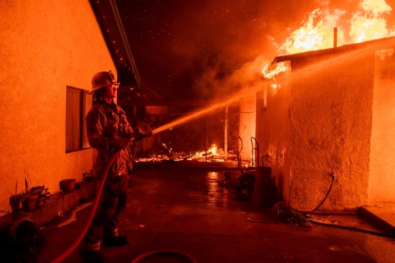 A firefighter sprays water on a garage burning in the Eaton Fire in Altadena, Calif., Jan. 8, 2025. (AP Photo/Nic Coury, File)